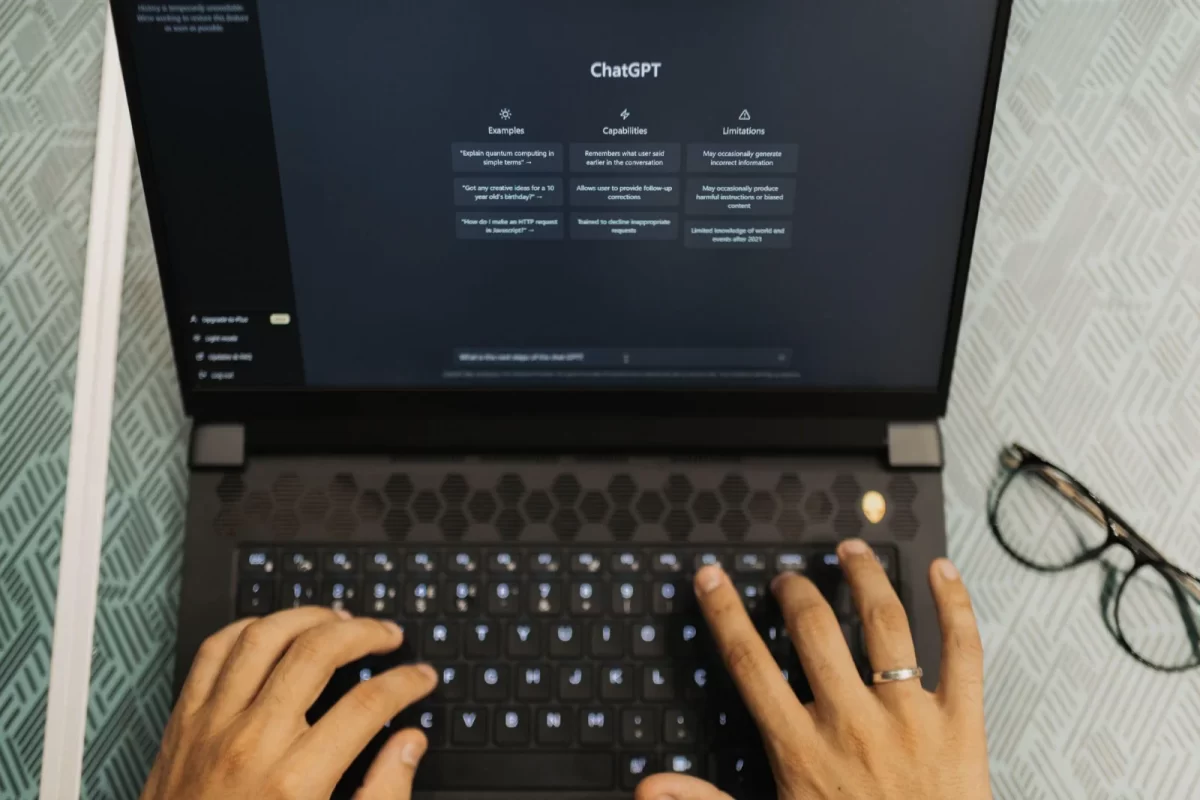 Hands typing on a laptop with ChatGPT open on the screen