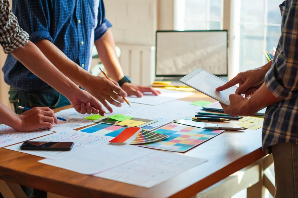 Design team reviewing colour swatches and website layouts on a table