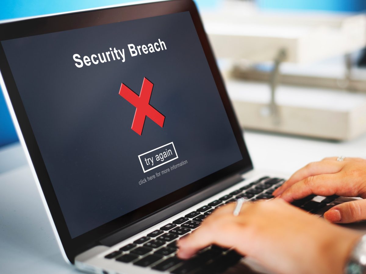 Laptop screen showing a security breach warning on a hacked website